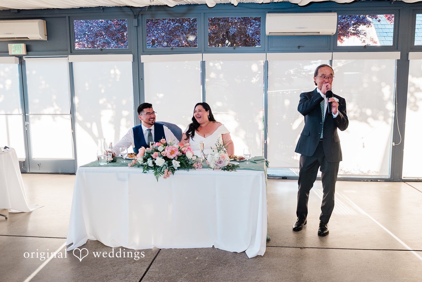 Bride and groom listening to the speech of a guest at reception