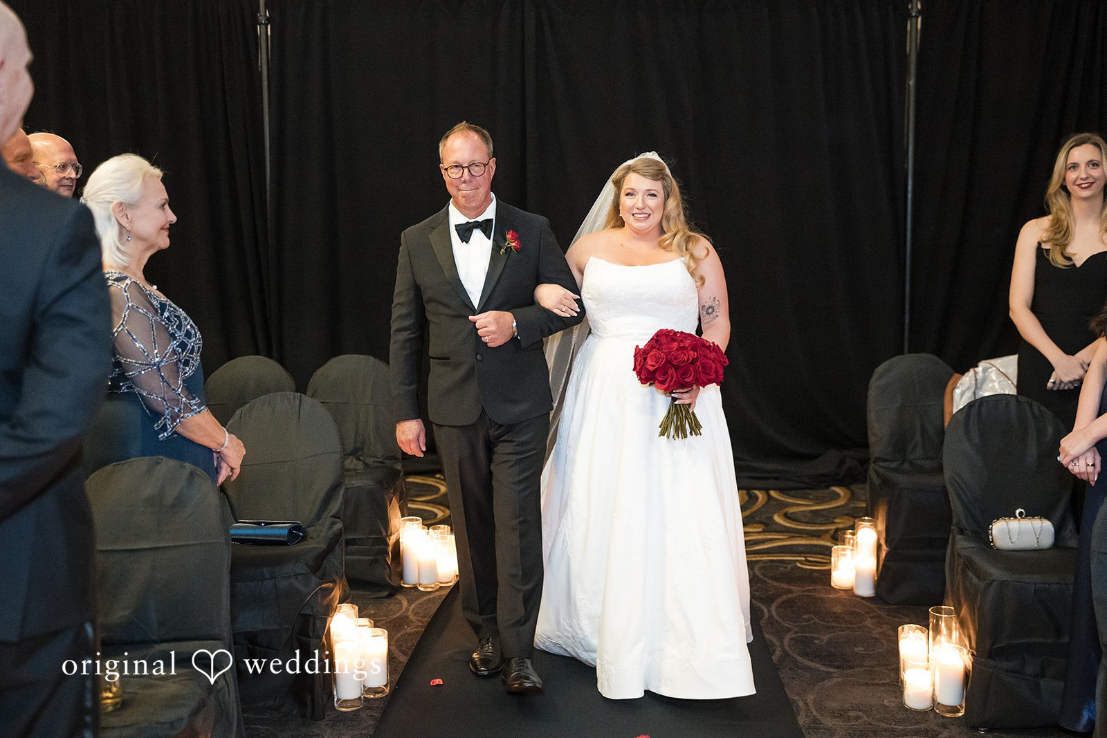 Bride walking down the aisle escorted by a man in a tuxedo.