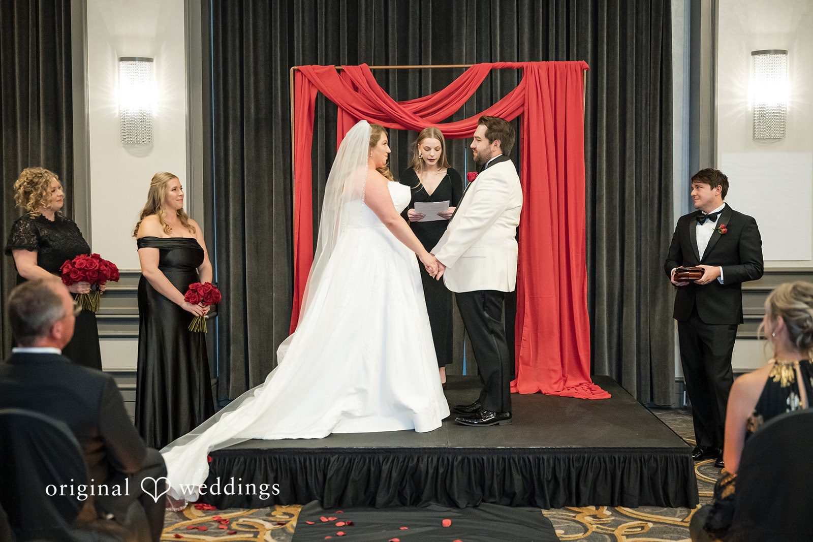 Wide shot of the bride and groom standing on a raised stage during their ceremony.