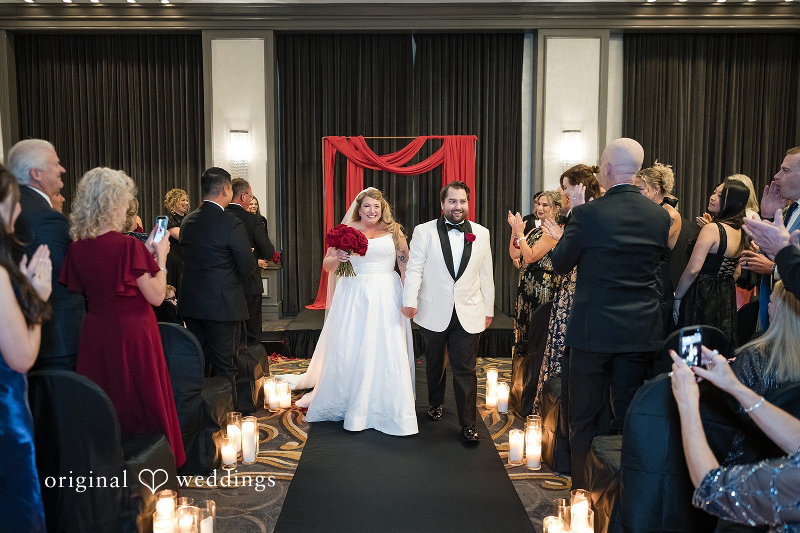 Bride and groom walking back down the aisle together as guests cheer.