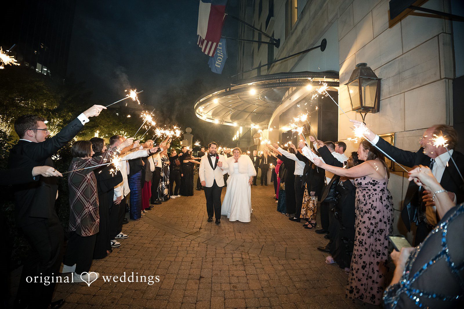 Wide shot of a wedding grand exit with guests lining the path holding sparklers.