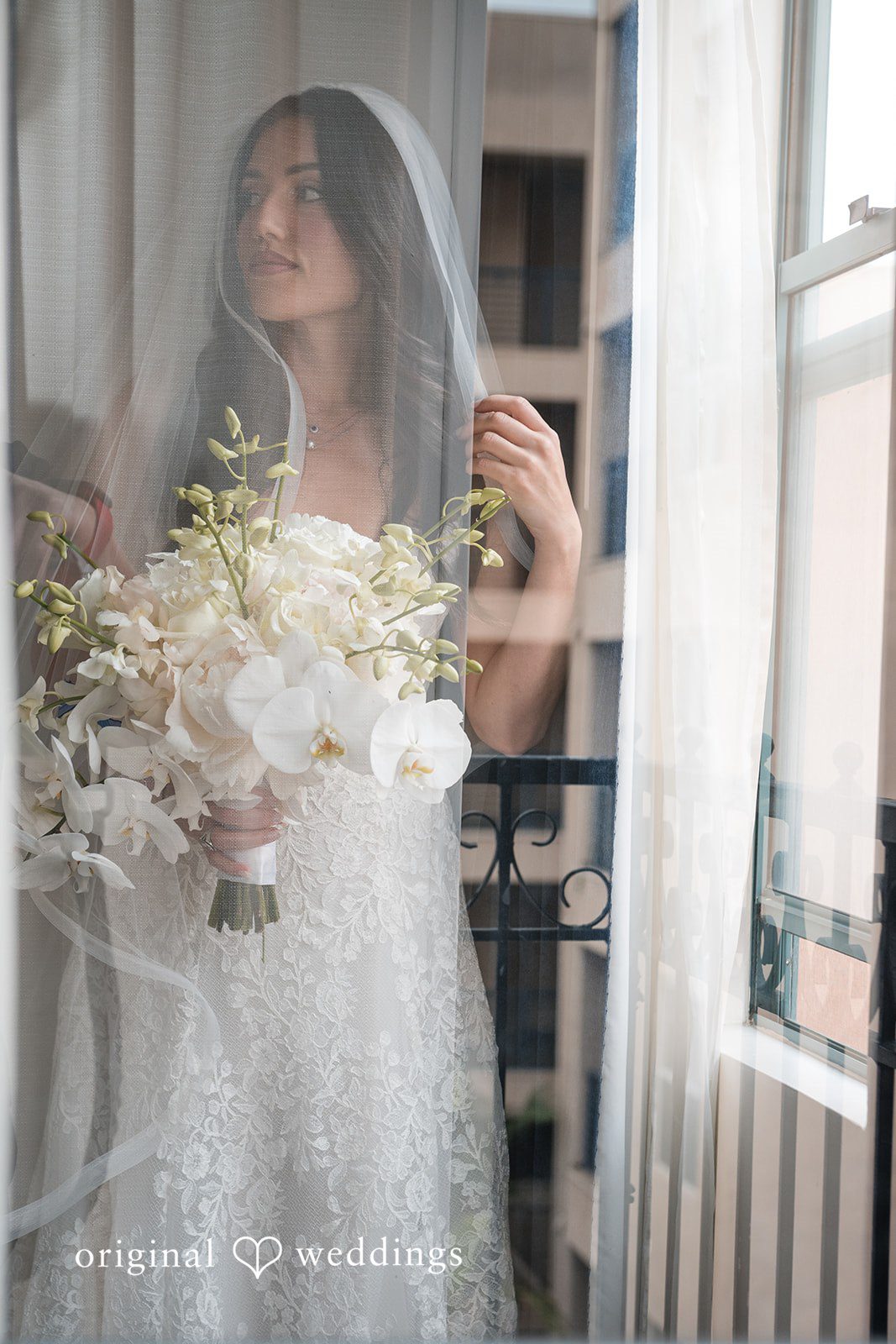 Tabatha + Justin A bride holding white flowers is captured through a soft, hazy lens effect.