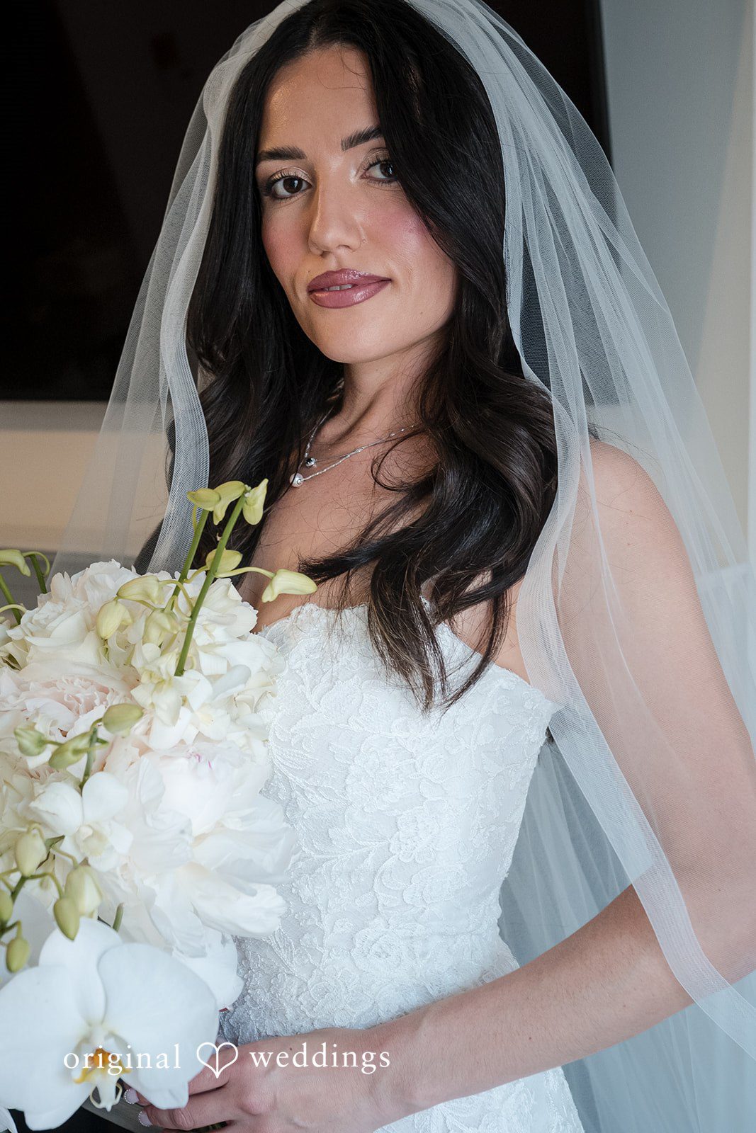 Tabatha + Justin A close-up portrait of a bride with long dark hair wearing a veil.
