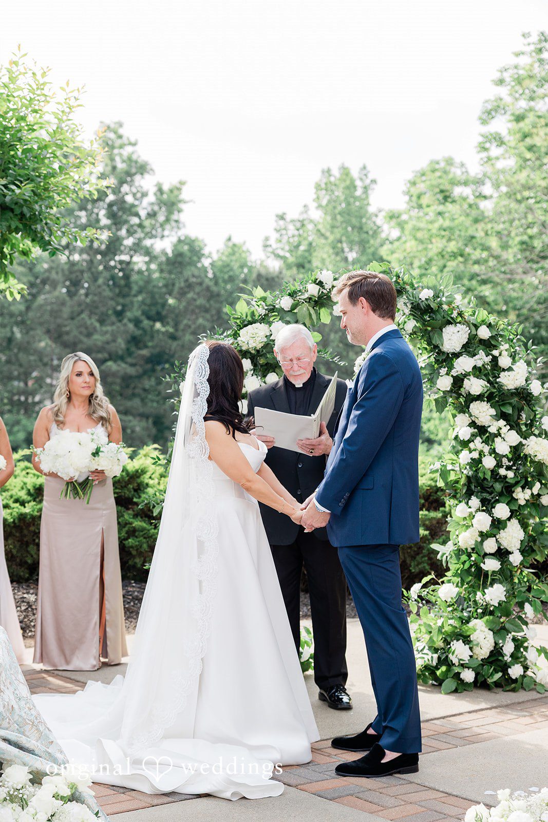 Anna + Blake Bride and groom listening to the priest while holding hands during ceremony