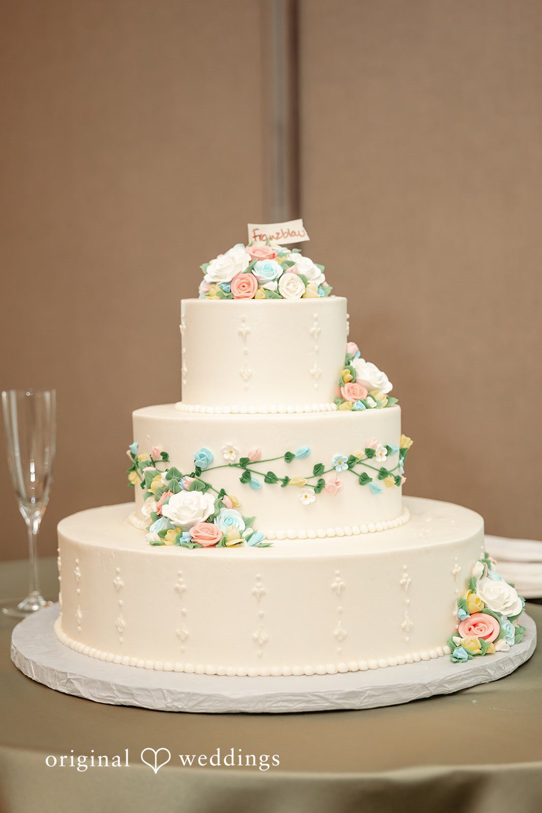 Sarah + Abby An all-white wedding cake adorned with florals