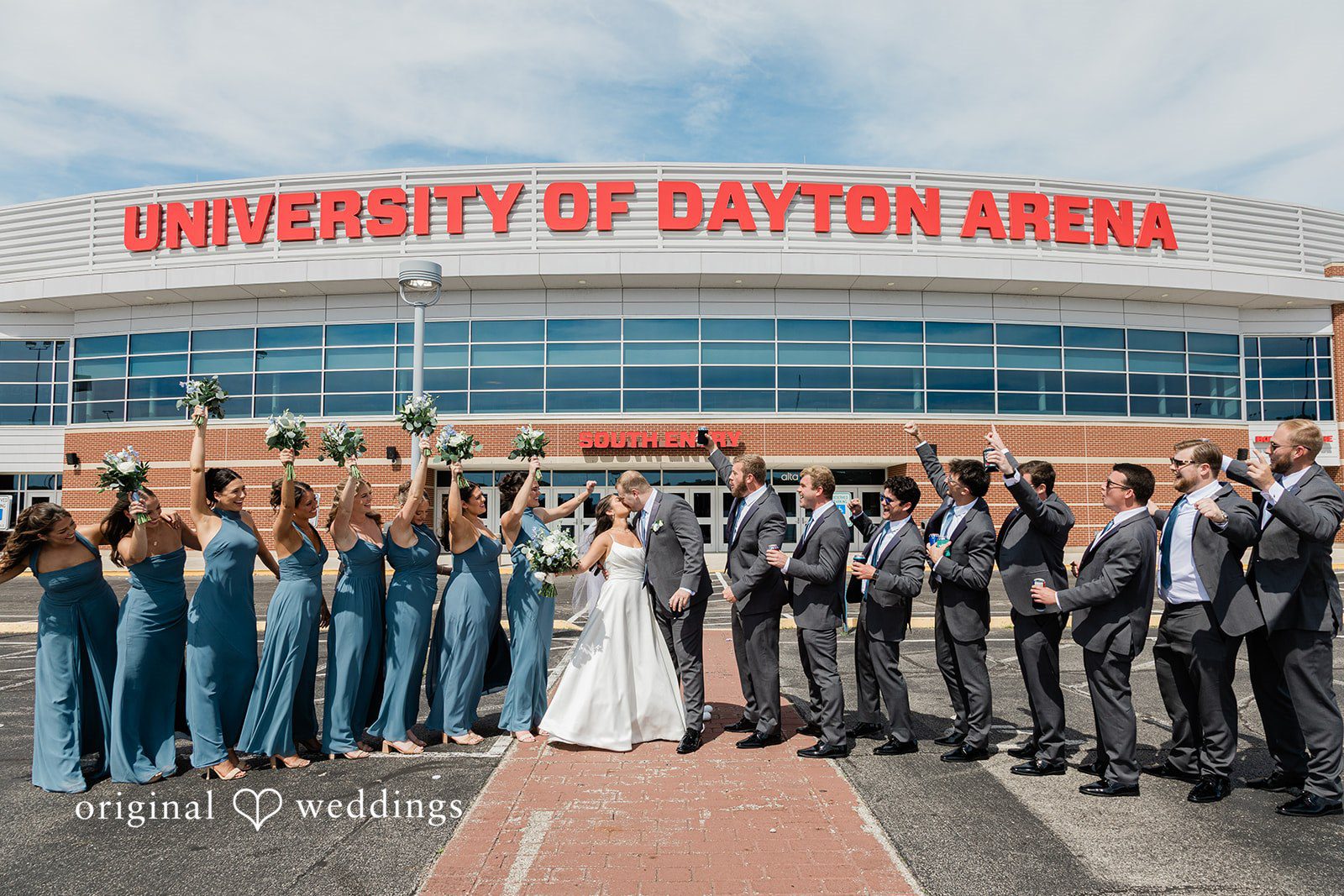 The couple takes a romantic shot at the University of Dayton Arena with cheers from their bridal party