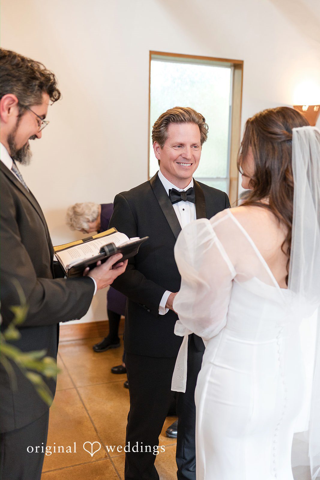 Bride facing away while groom stands at the ceremony