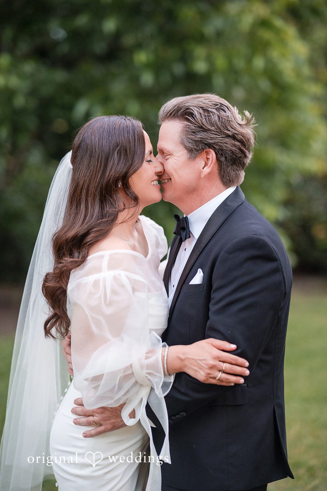 Bride and groom sharing a romantic kiss outdoors