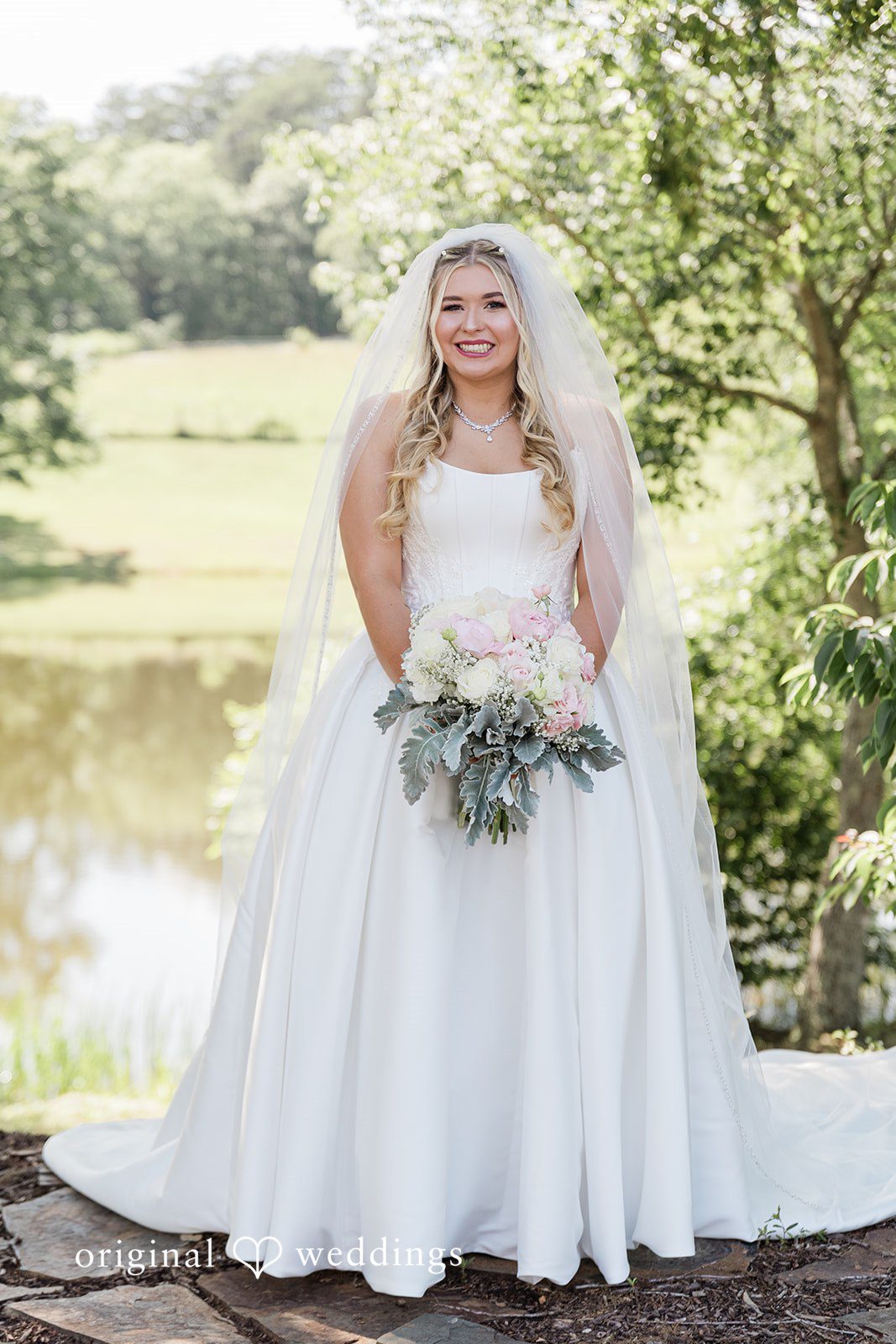 Bride in a white wedding gown holding a green bouquet at Luna's Trail Venue.