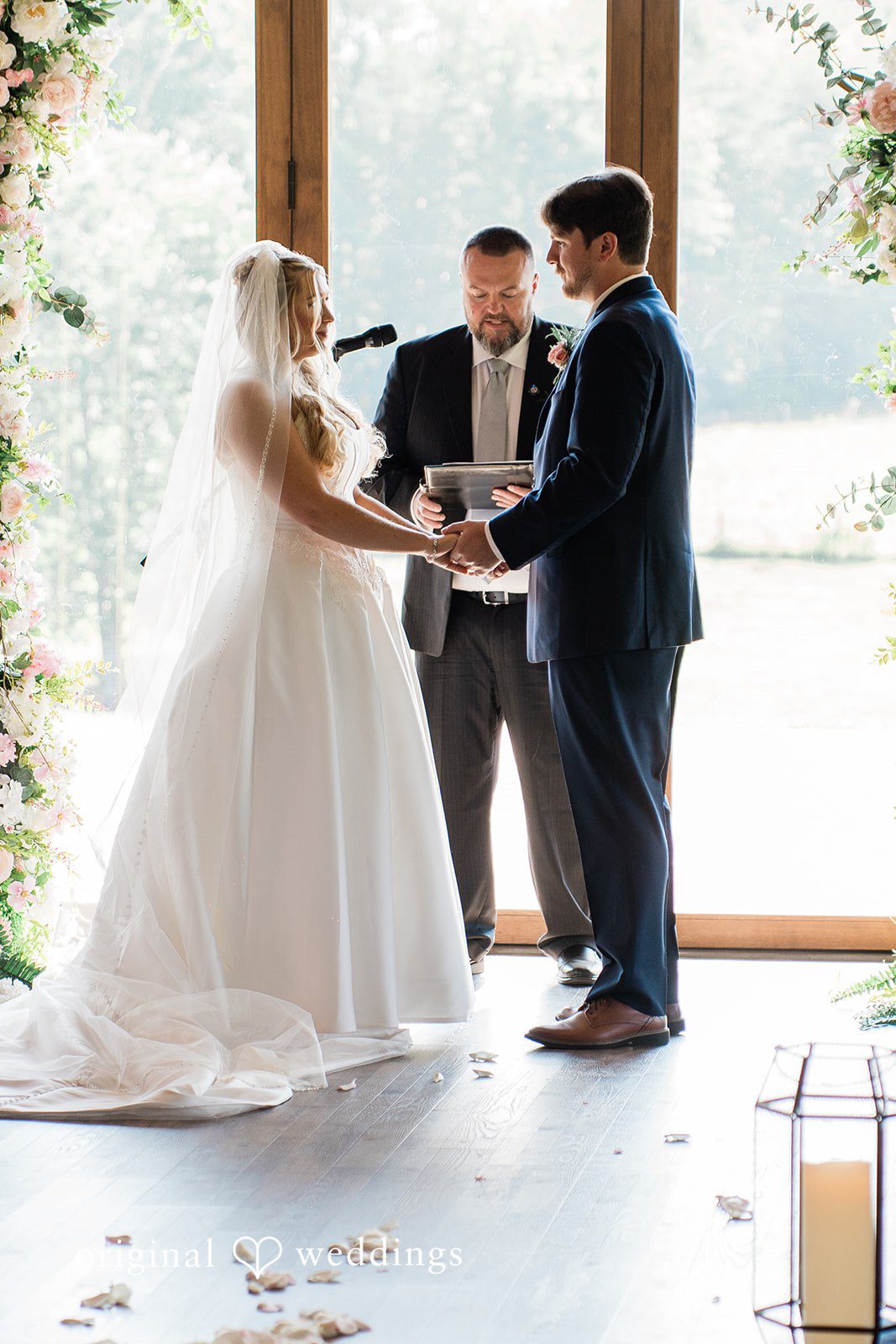 Side profile view of a bride and groom exchanging vows in front of a bright window.