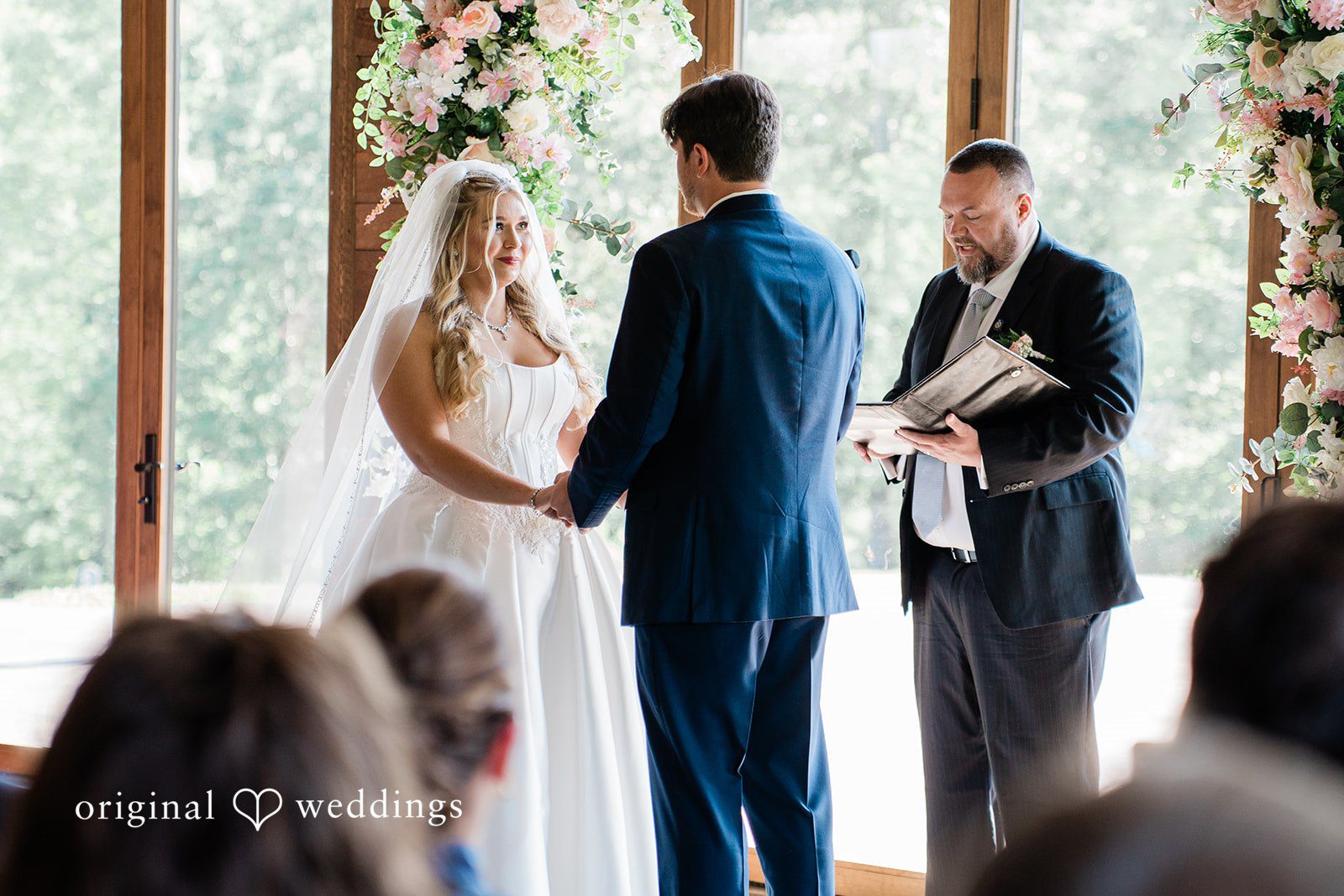 Bride and groom holding hands in front of an officiant during their wedding ceremony.