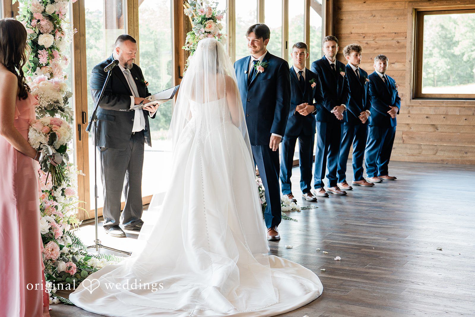 Wide shot of a bride and groom standing at the altar with their wedding party .