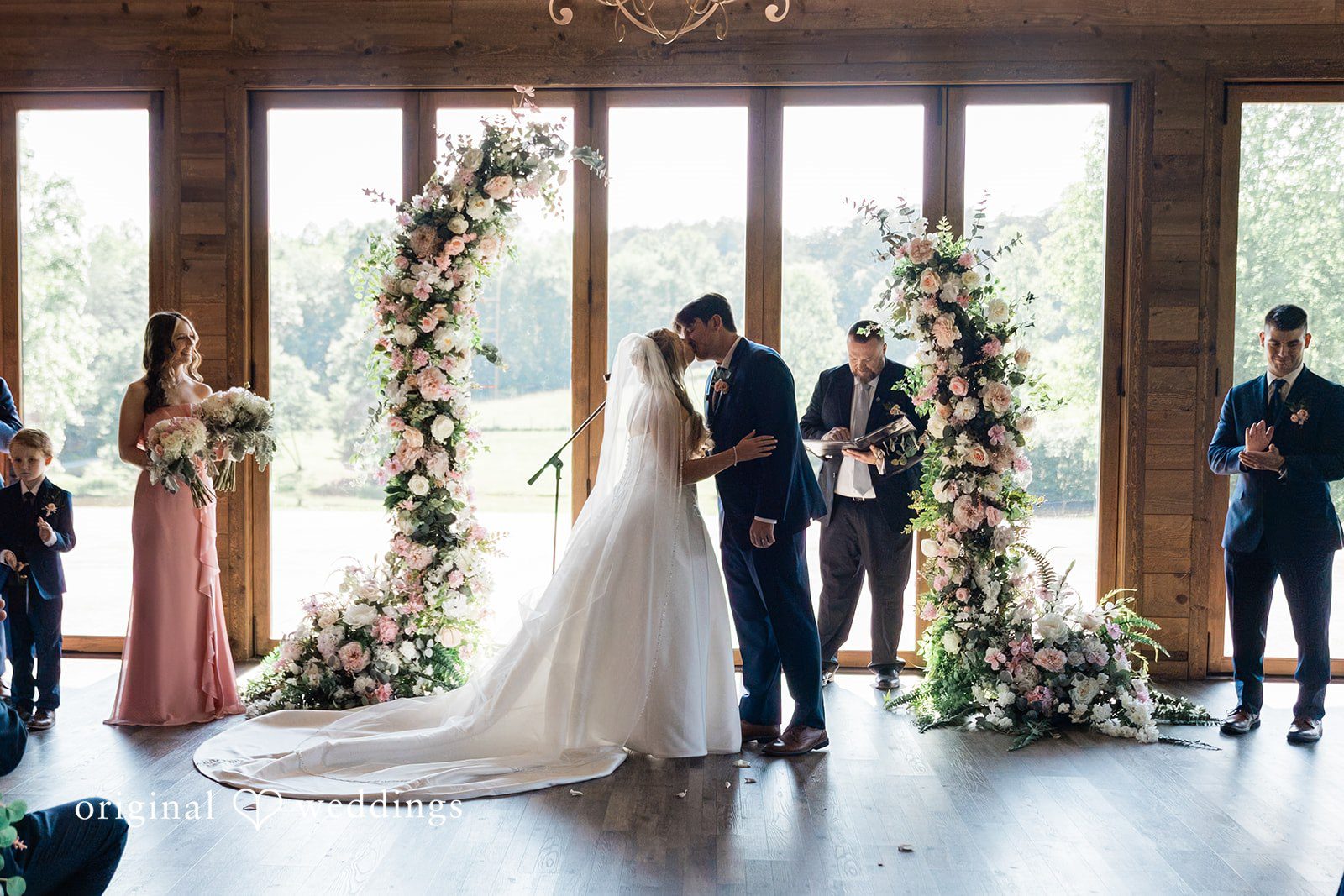 Bride and groom sharing their first kiss at the altar in front of seated guests.