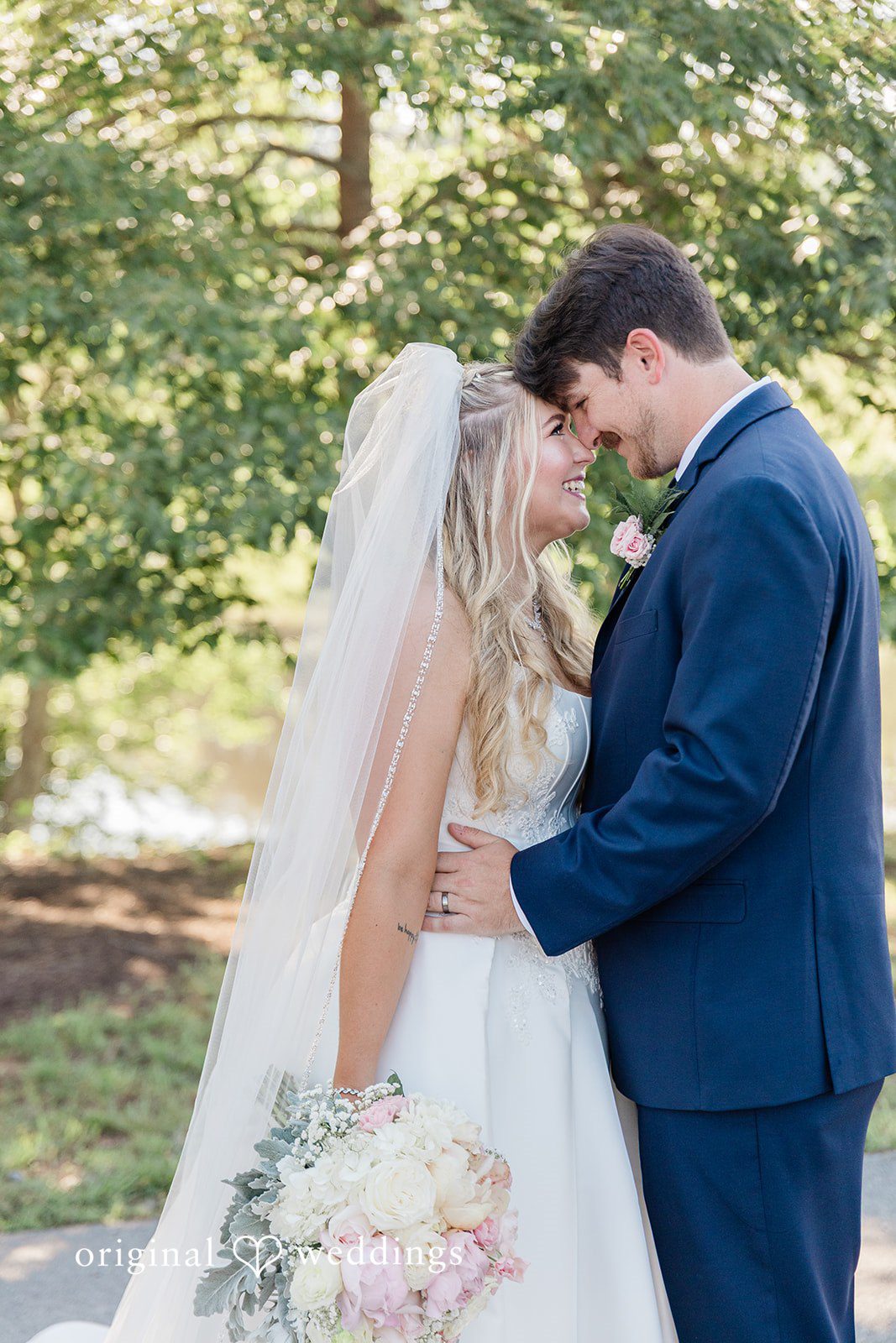 Bride and groom leaning their foreheads together affectionately while smiling.