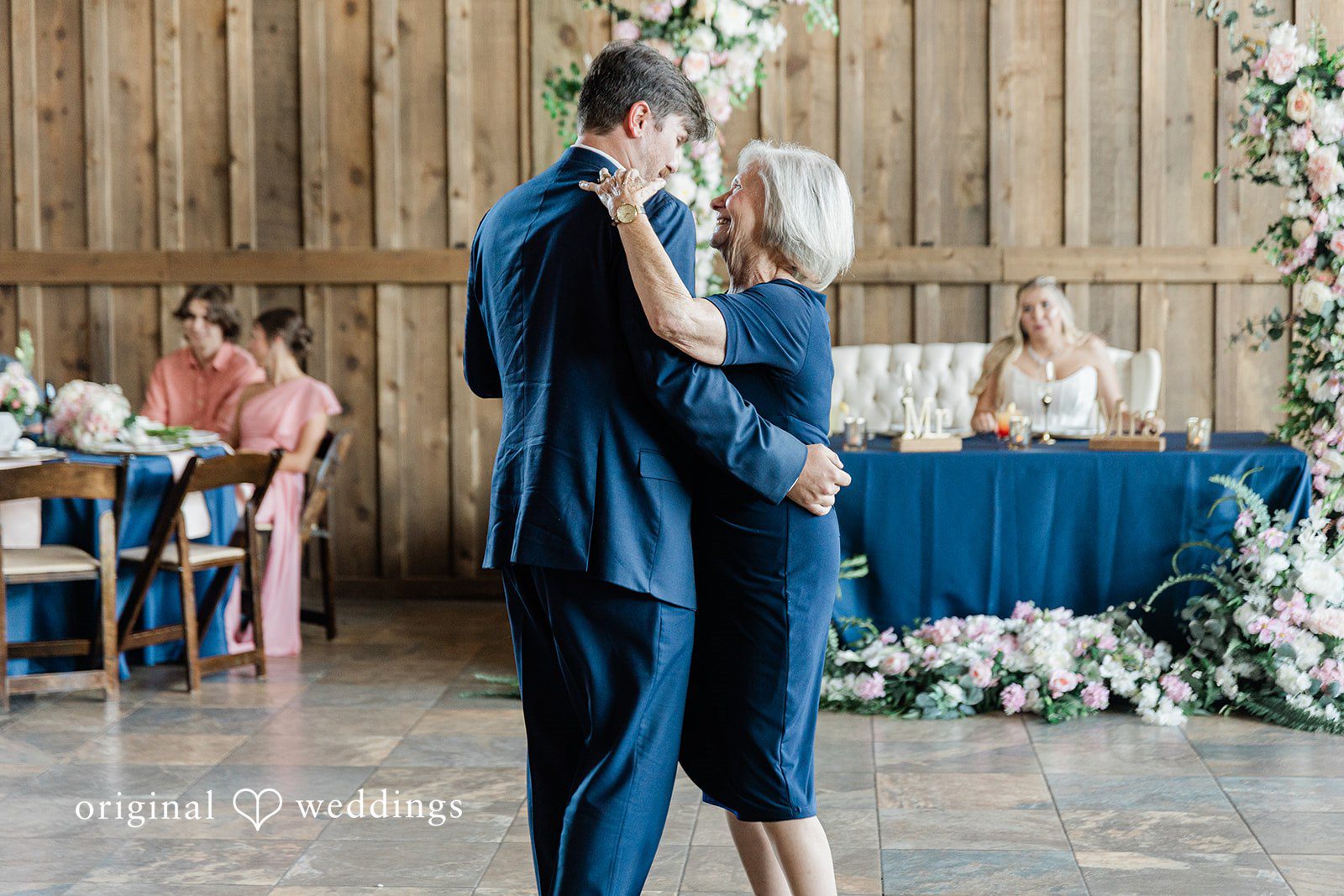Groom sharing a dance with a woman wearing a navy blue knee-length dress.