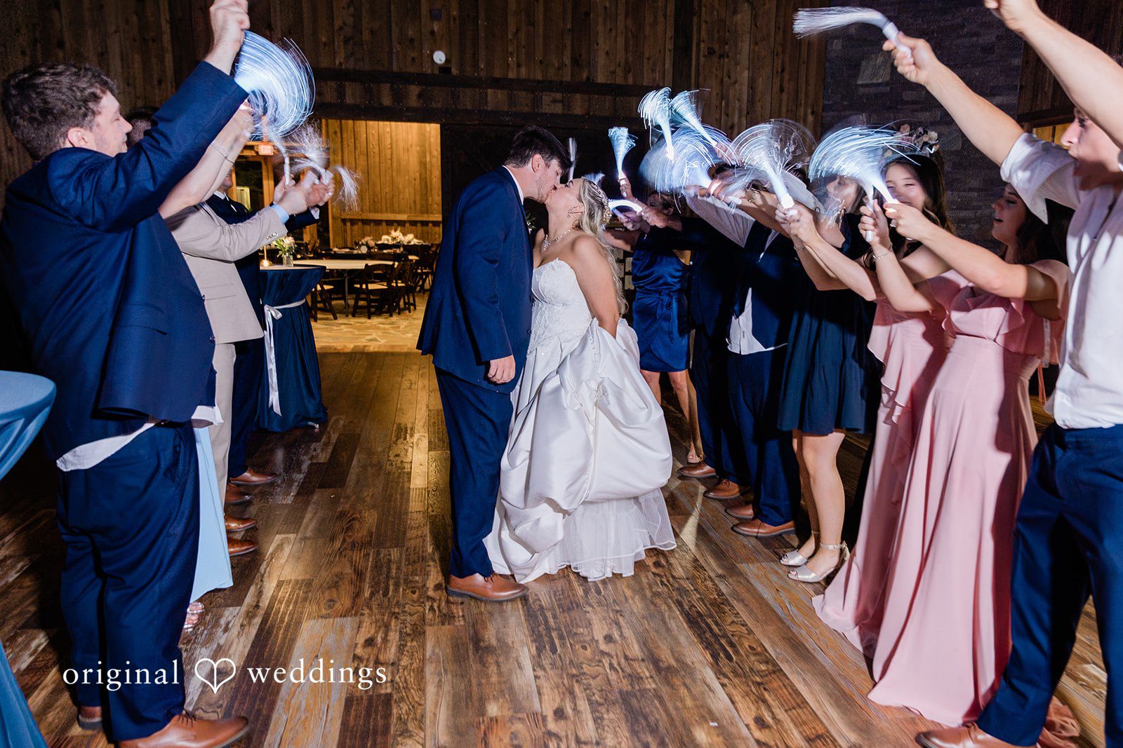 Wedding guests waving white fiber optic wands to create a grand send-off tunnel for the bride and groom.