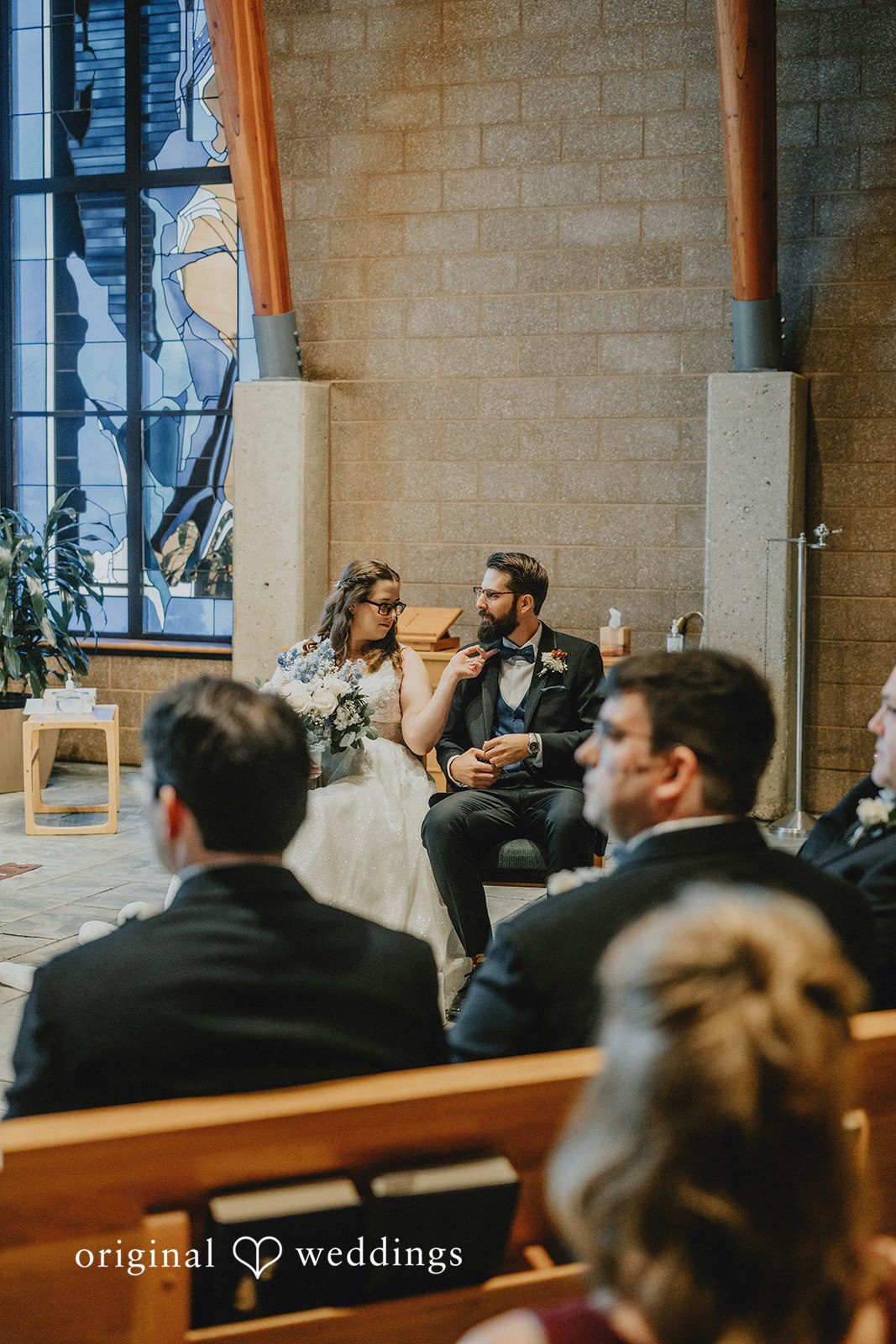 Daniel + Amanda Guests sitting in wooden pews watching a wedding ceremony.
