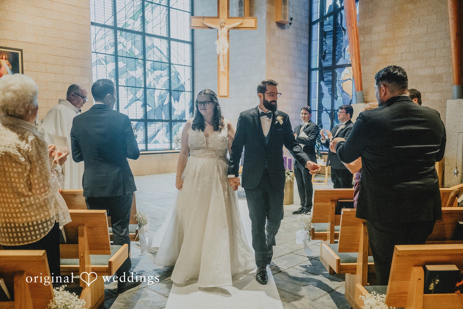 Daniel + Amanda A bride and groom holding hands and walking down the church aisle together.
