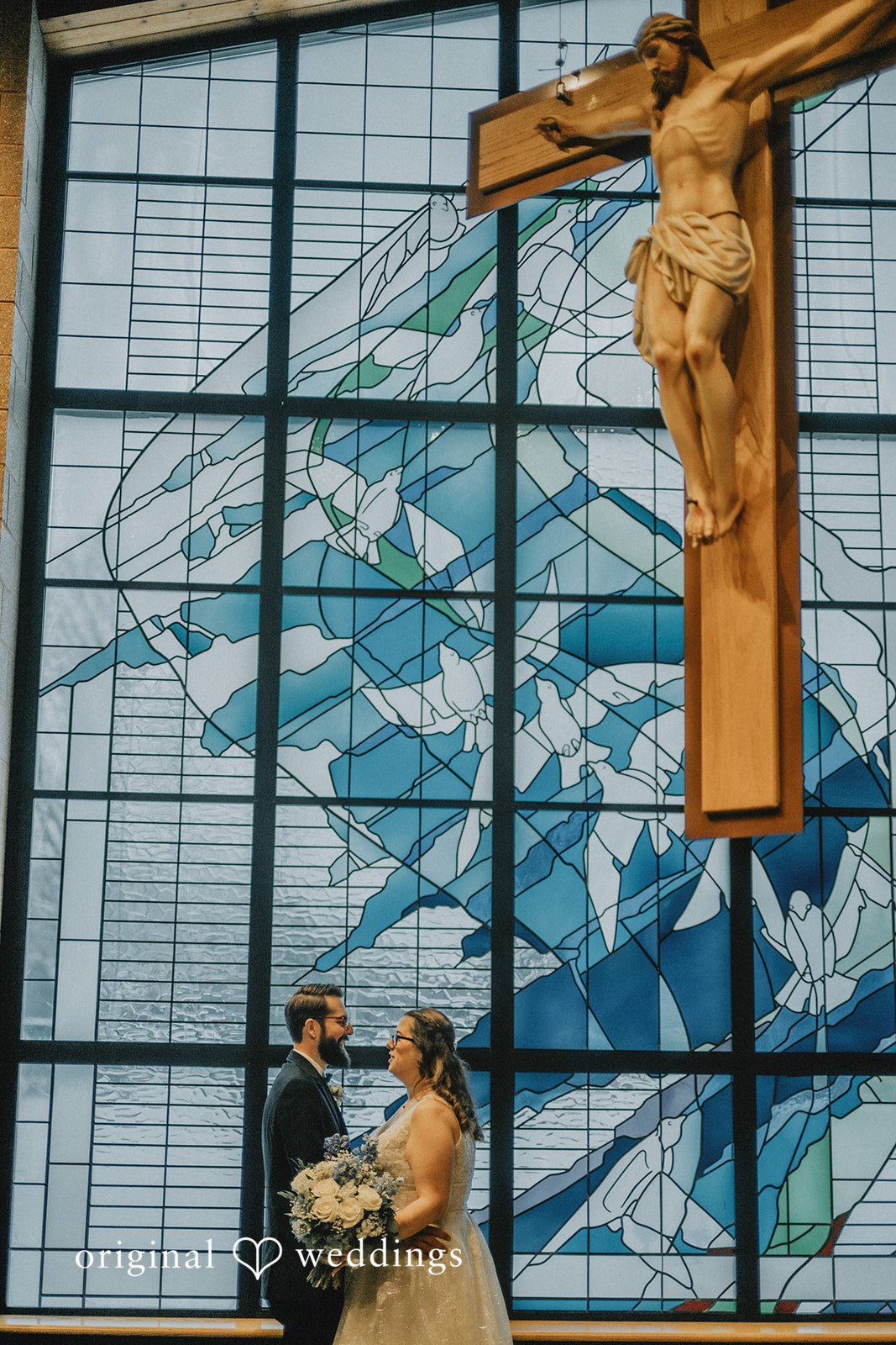 Daniel + Amanda A bride and groom standing before a large stained-glass window.
