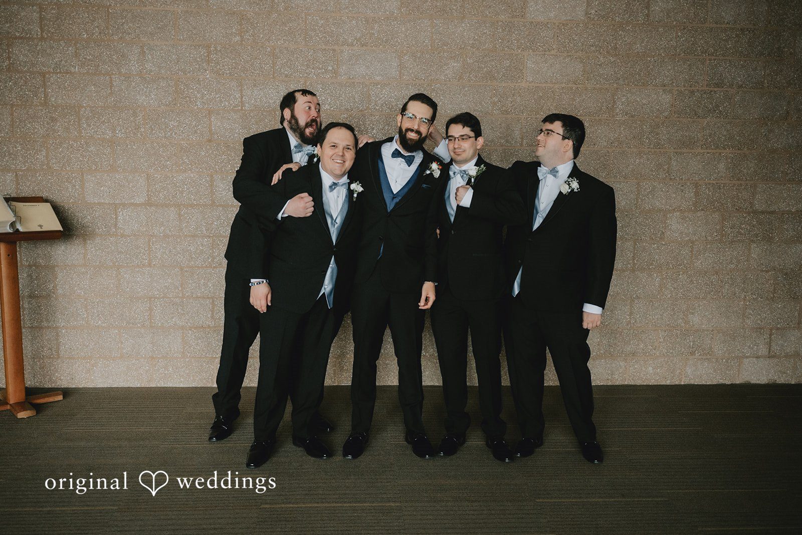 Daniel + Amanda Groom and groomsmen in black suits standing together and laughing.