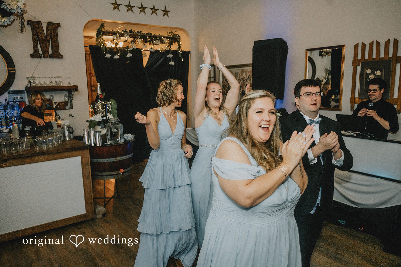 Daniel + Amanda Bridesmaids in light blue dresses cheering and dancing at a reception.