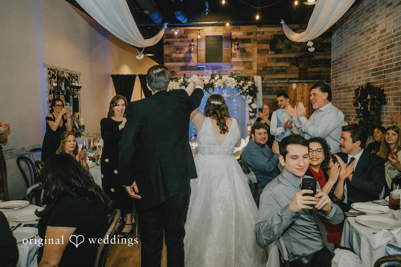 Daniel + Amanda A bride and groom entering their reception hall as guests applaud.