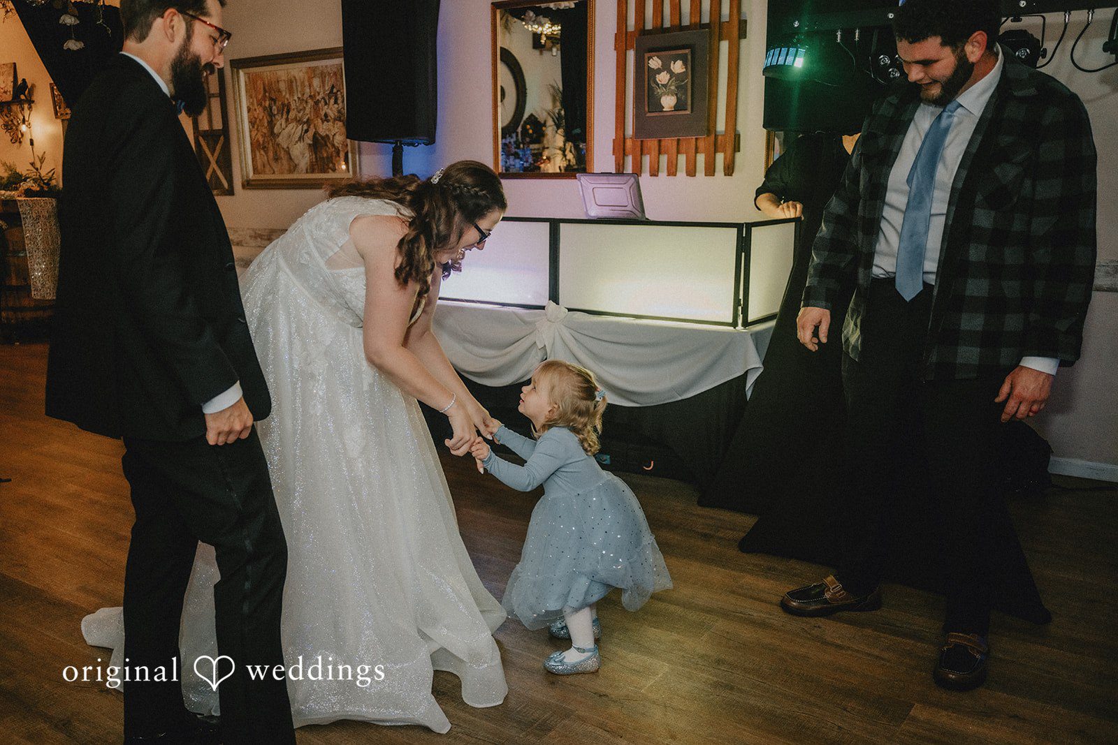 Daniel + Amanda A bride bending down to hold a young girl's hand.