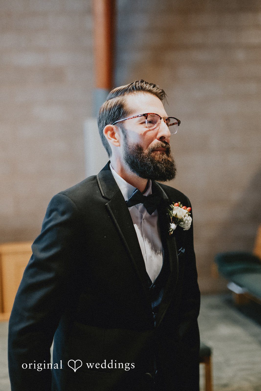 Daniel + Amanda A groom with a beard and glasses looking to the side in a black suit.