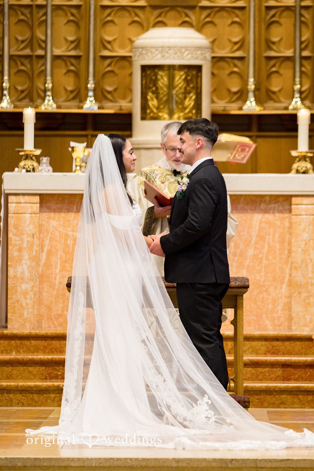 Kiarra + Anthony Elegant couple standing before priest while holding hands at Nativity of Our Lord Catholic Church