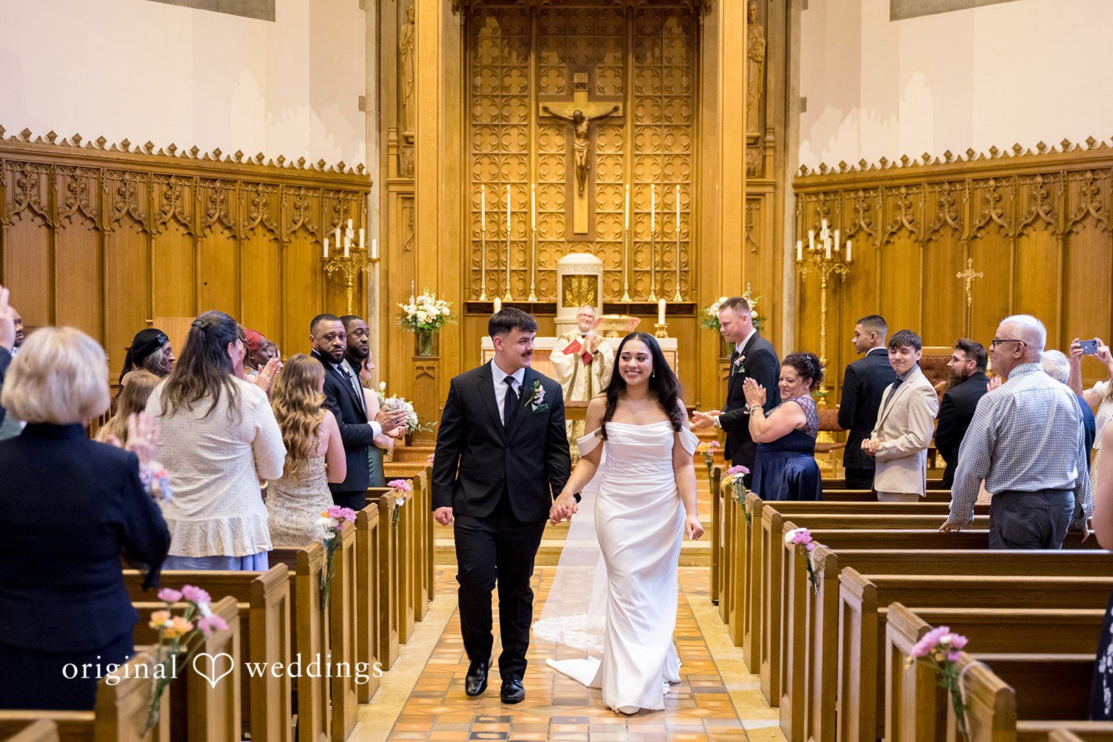 Kiarra + Anthony Minneapolis Wedding Photographers capturing the groom and bride walking outside together as they exit at Nativity of Our Lord Catholic Church by Original Weddings