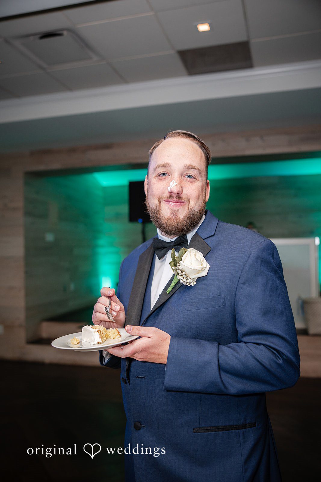 Groom enjoying a bite of wedding cake at the reception