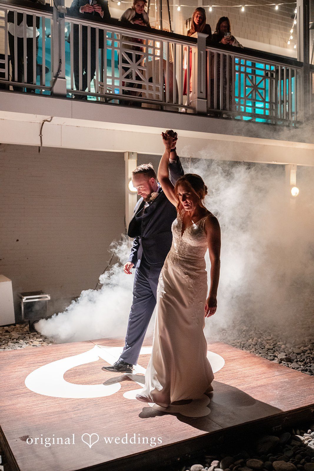 Bride and groom raising their hands while dancing in reception fog effects at Oceanview of Nahant
