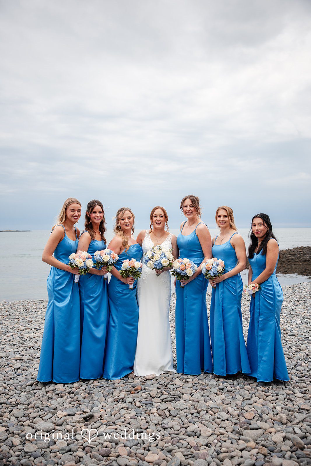 Bride and bridesmaids posing together along the shoreline