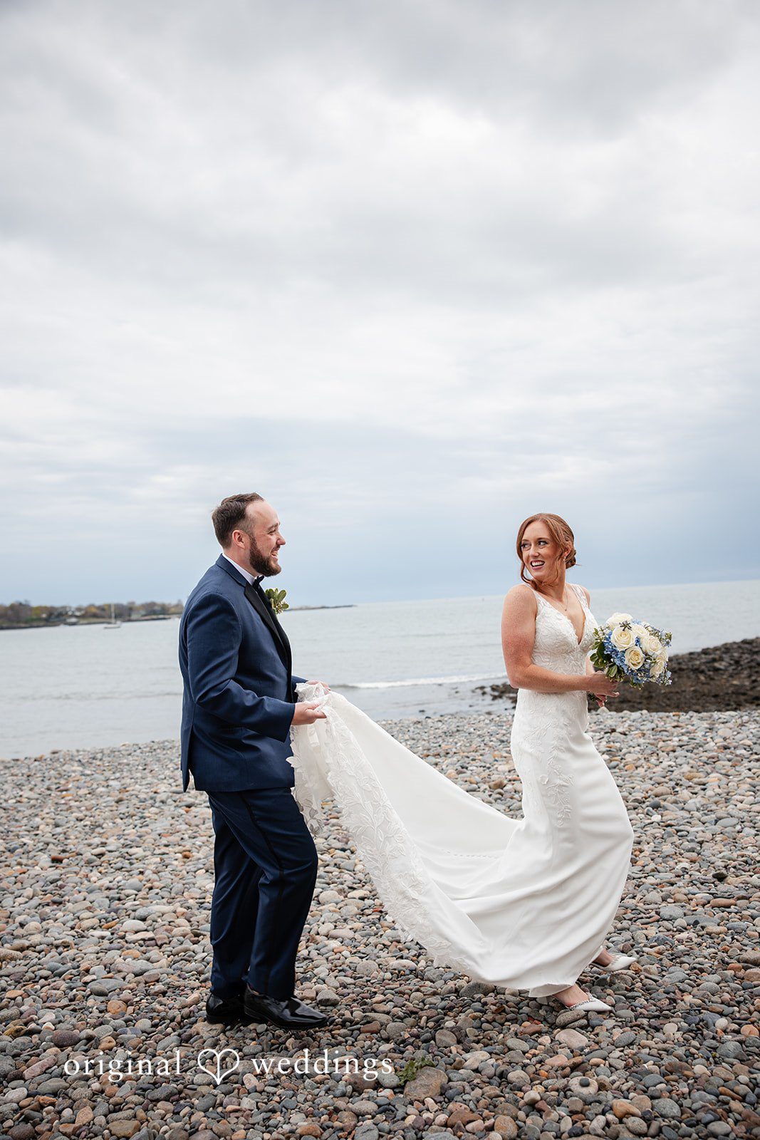 Newlyweds standing side by side with ocean views behind them