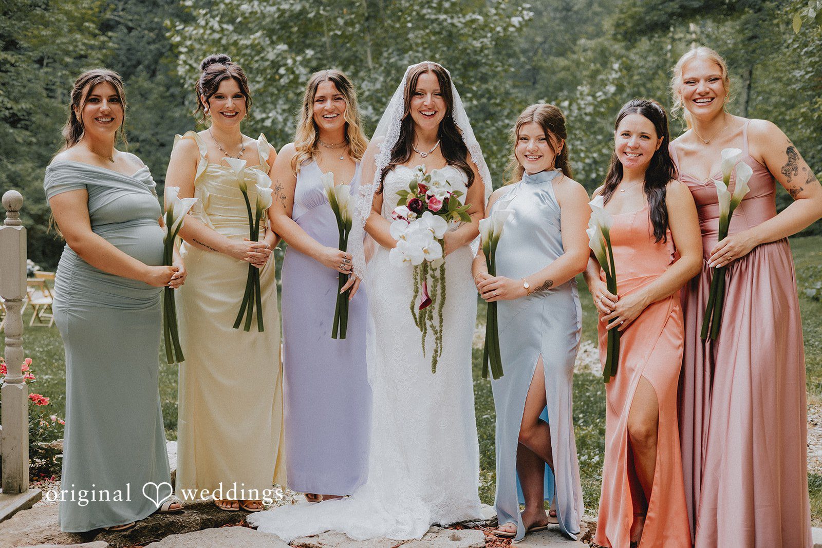Lovely group picture of bride with bridesmaids, all smiling and holding flowers
