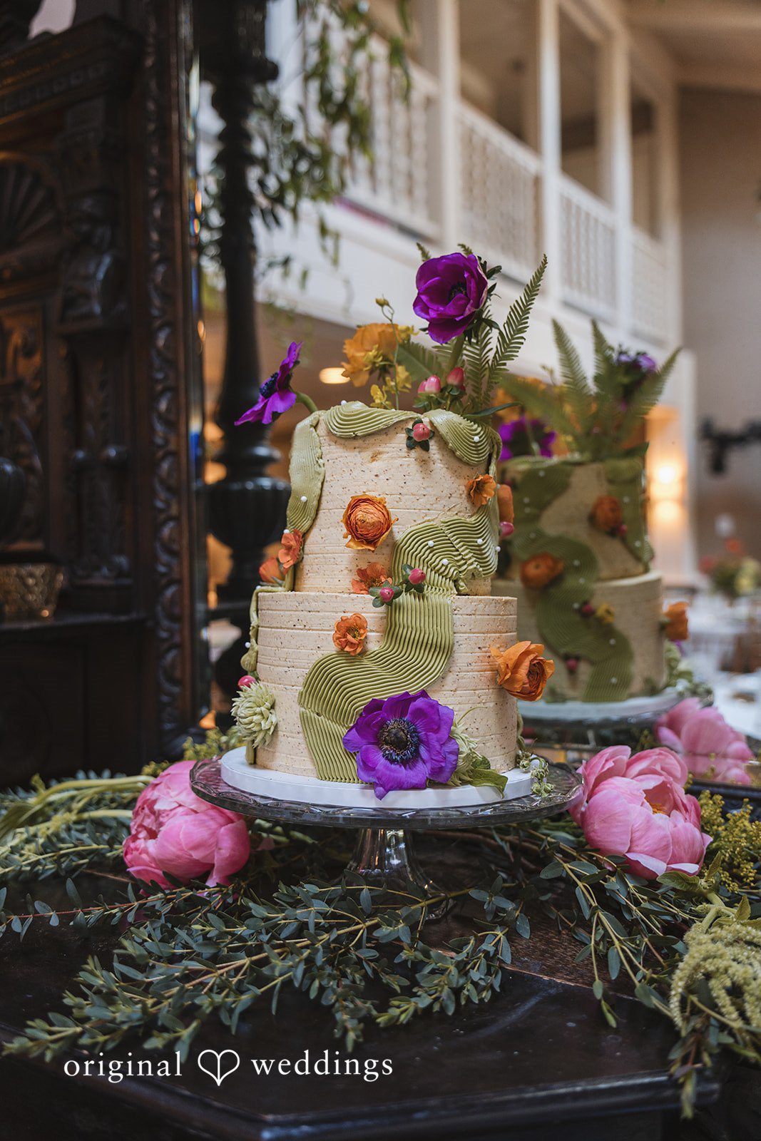 Benjamin + Amber A beautifully decorated floral wedding cake with vibrant blooms displayed at the reception inside Outlook Inn.