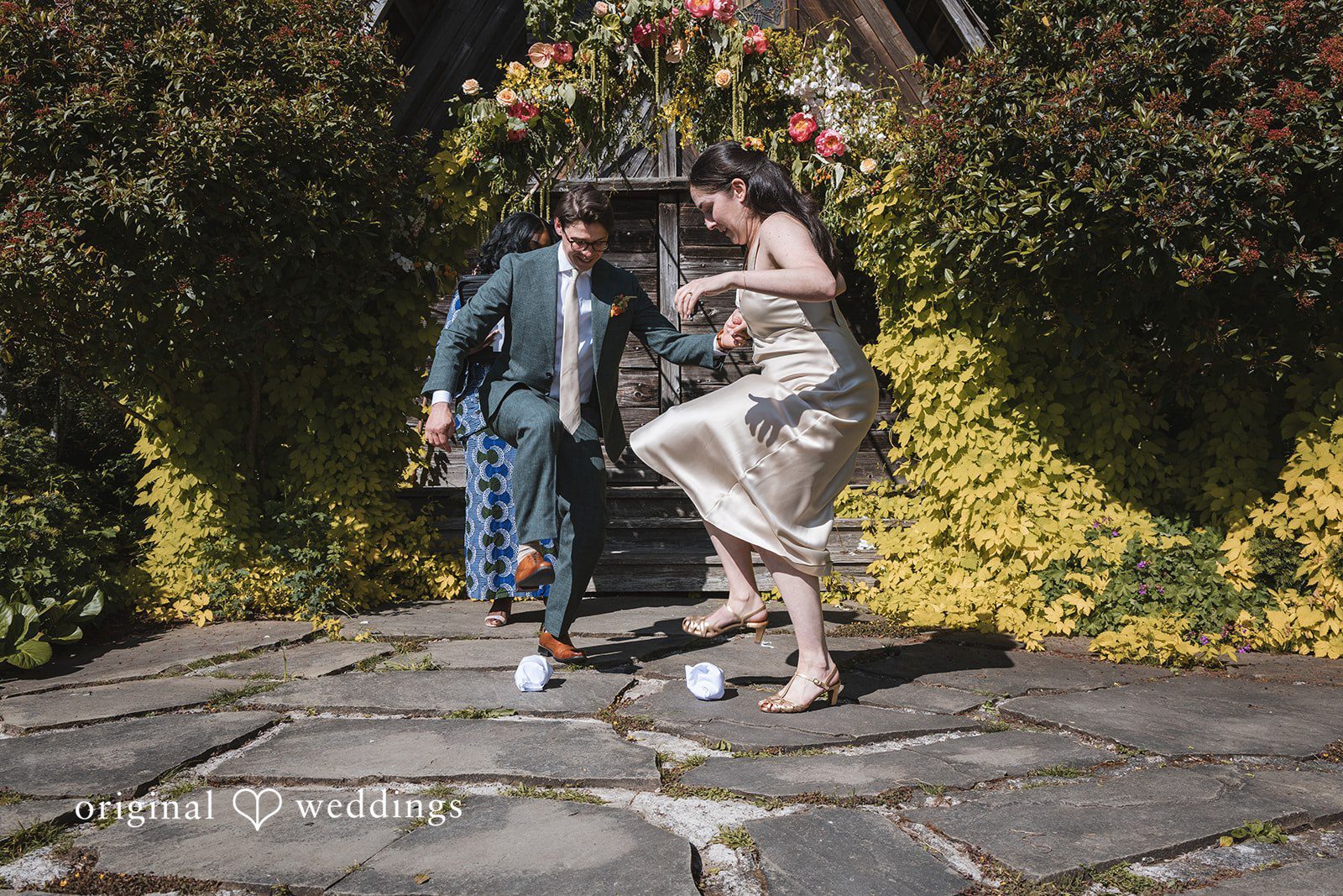 Benjamin + Amber The couple shares a playful moment stepping on glasses during their wedding celebration at Outlook Inn.