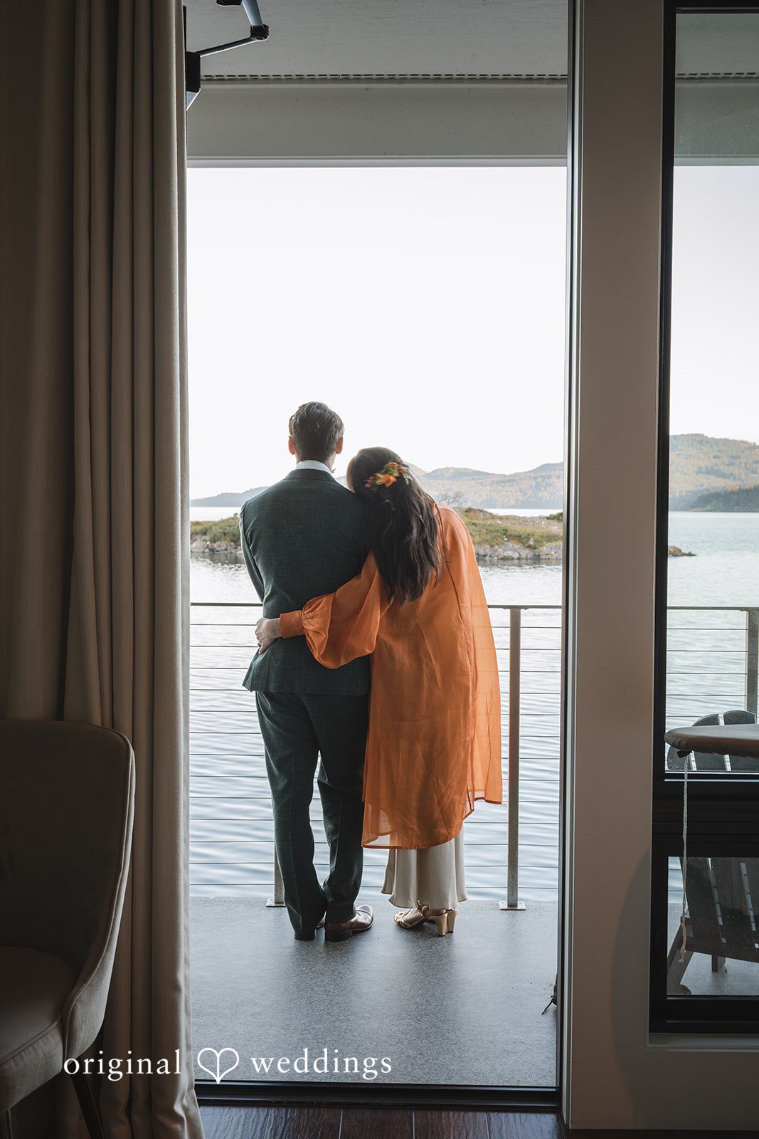 Benjamin + Amber The couple shares a quiet, romantic moment overlooking the water from a balcony after their wedding celebration