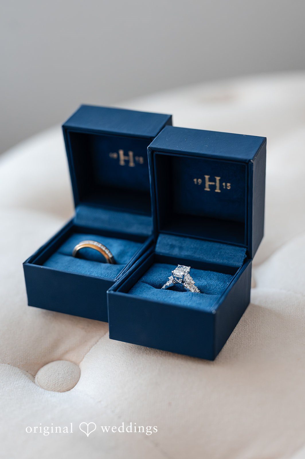 Two wedding bands displayed in open blue jewellery boxes.