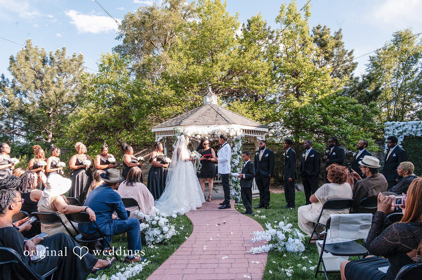 A wide view of a wedding ceremony with guests seated as the bride and groom stand at the altar.