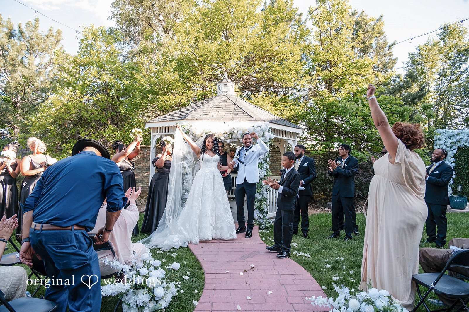 A bride and groom walking down the aisle together as wedding guests celebrate.