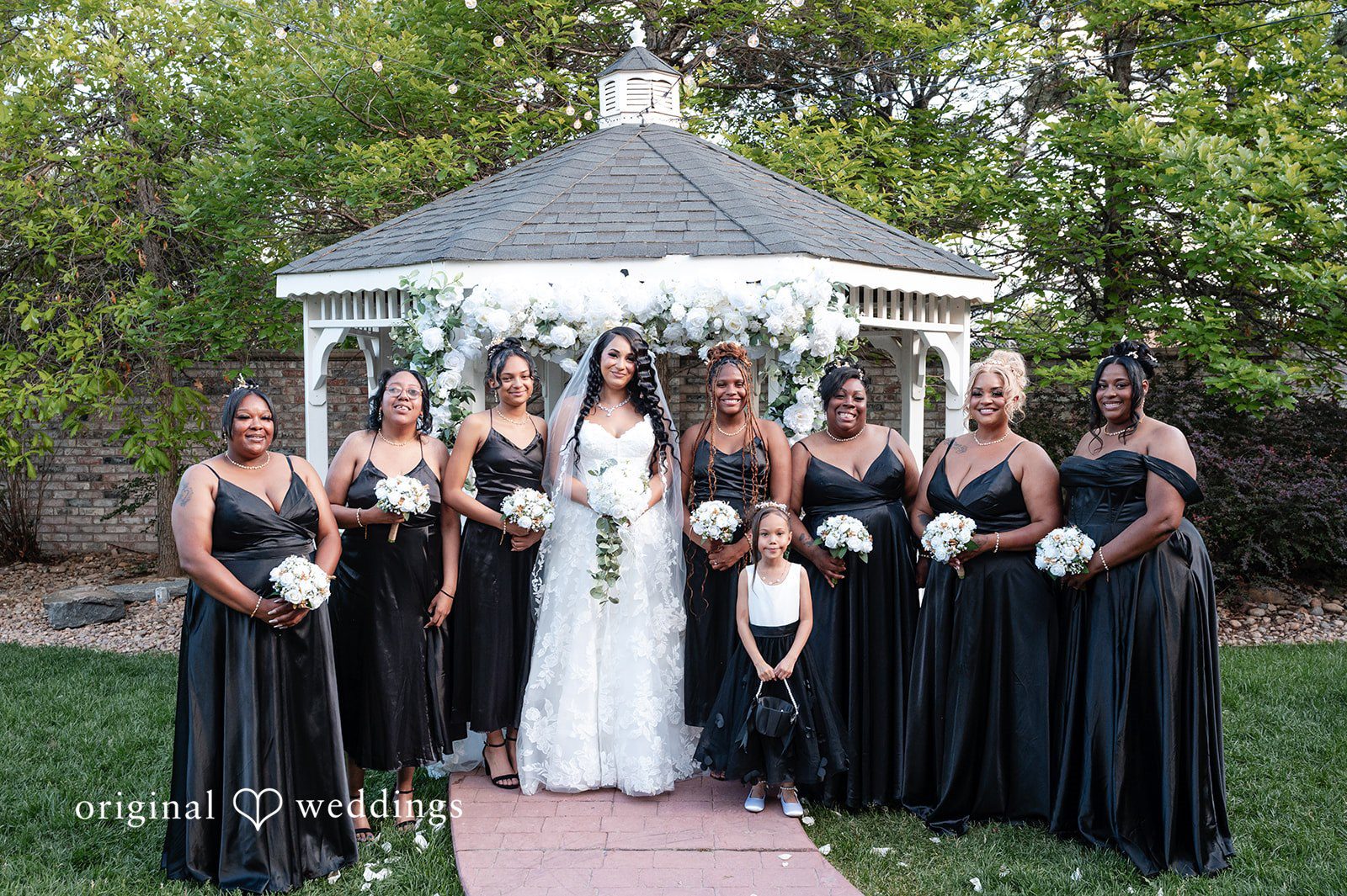 bride standing with her bridesmaids wearing long black dresses at Radiance Event Center.