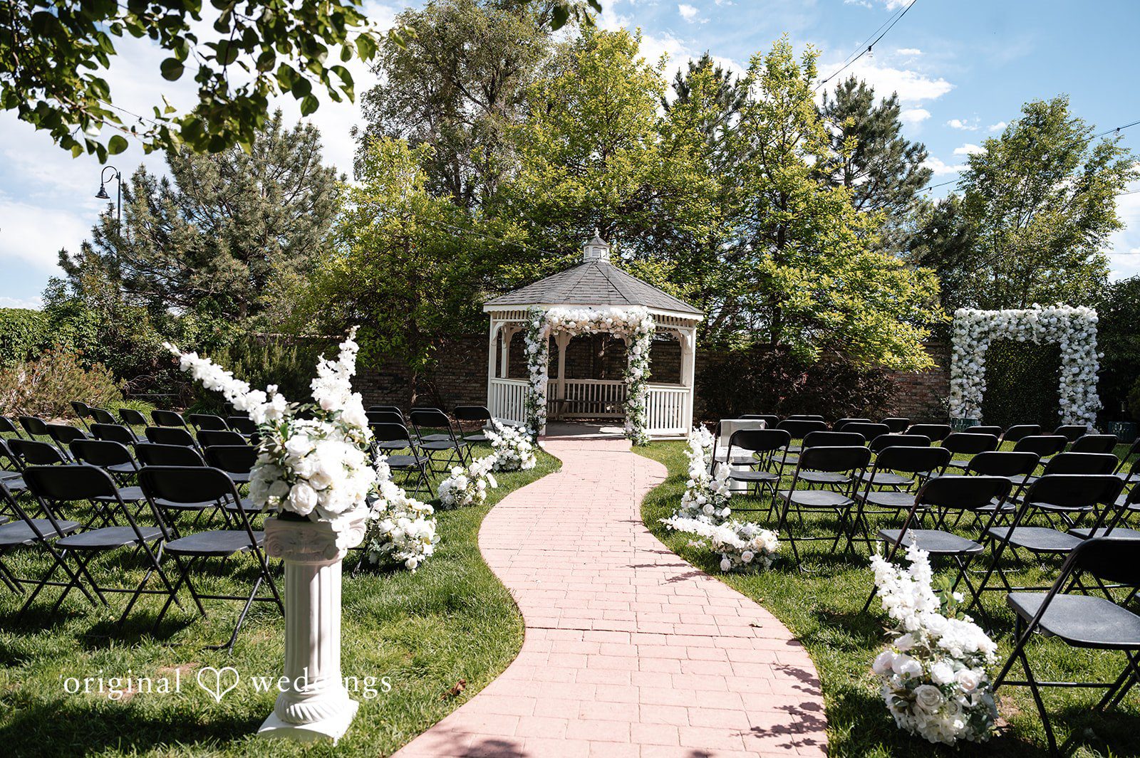 A wedding ceremony setup featuring an aisle runner leading to a white gazebo.