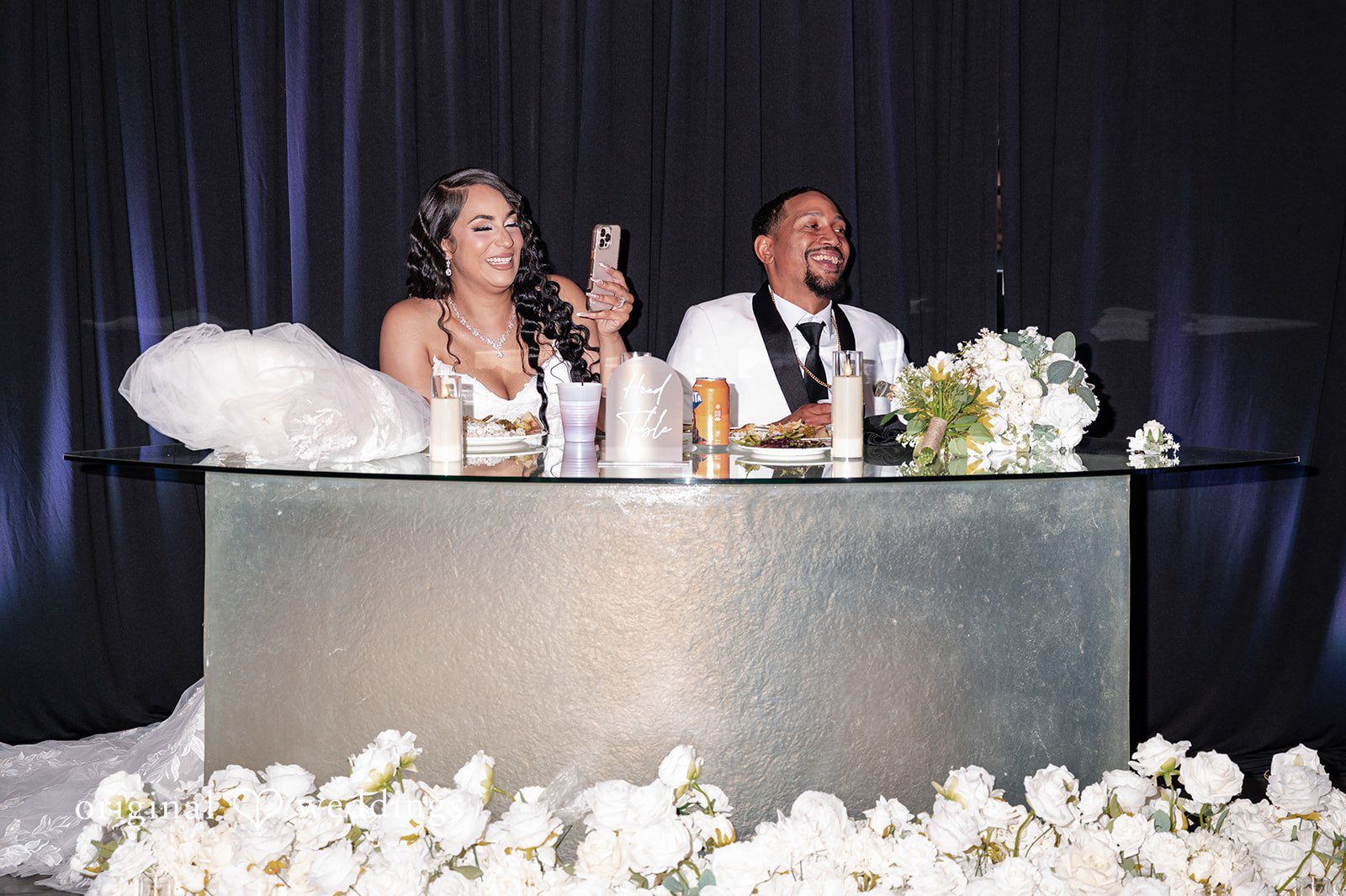 A bride and groom sitting at their elevated sweetheart table during a reception.