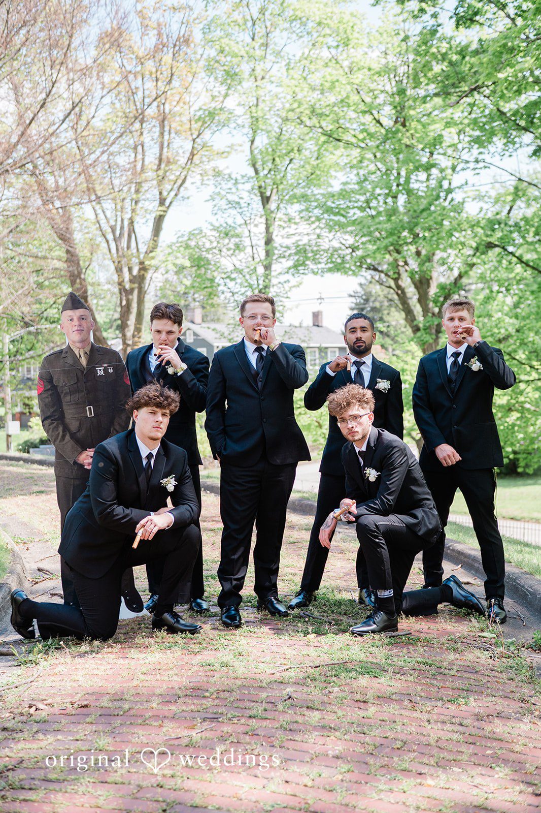 Groom and groomsmen posing together beneath the trees