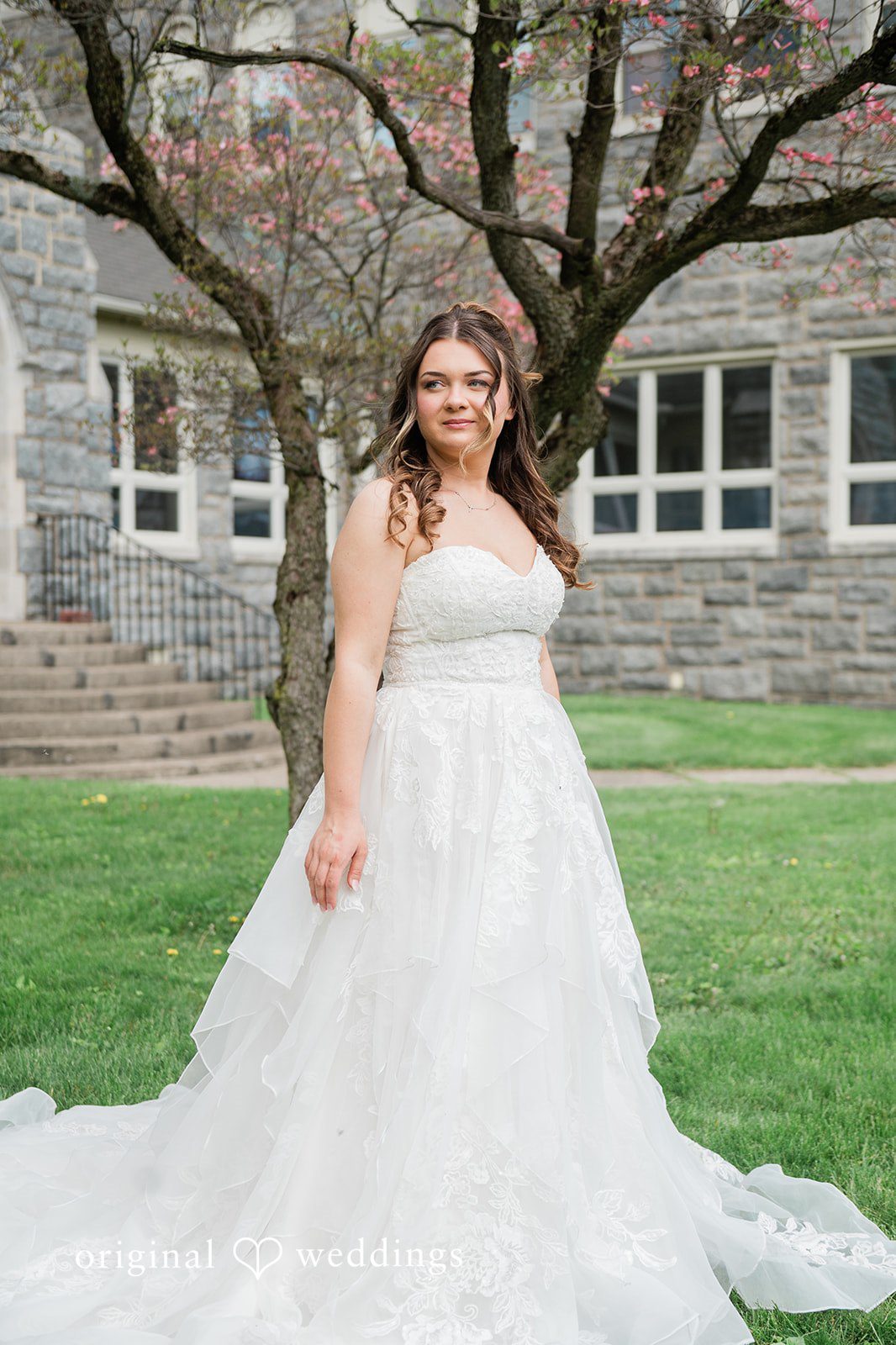 Full-length portrait of the bride beside a tree outside the venue