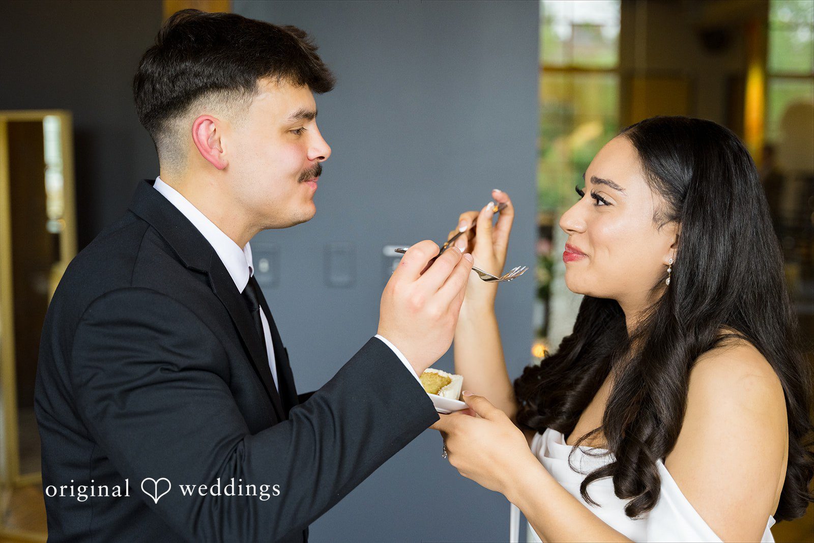Kiarra + Anthony Minneapolis Wedding Photographers capturing the couple feeding cake to each other at Solar Arts by Original Weddings