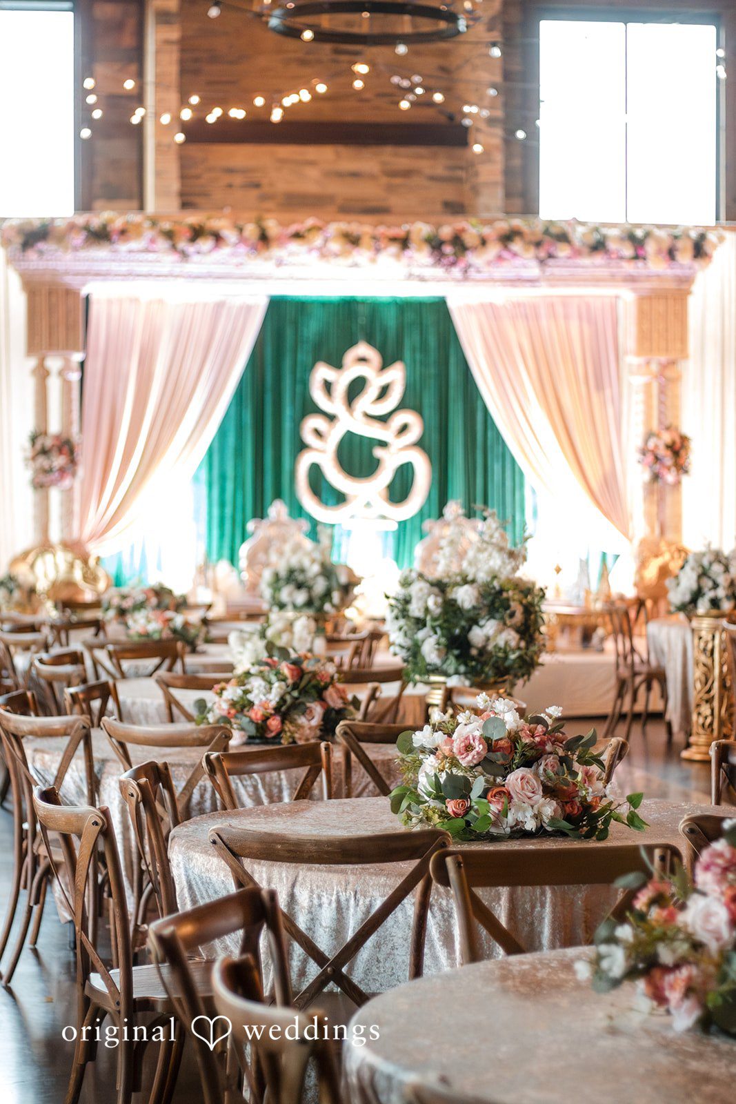 A banquet setup featuring a long wooden table in front of a draped backdrop with a green circular emblem.