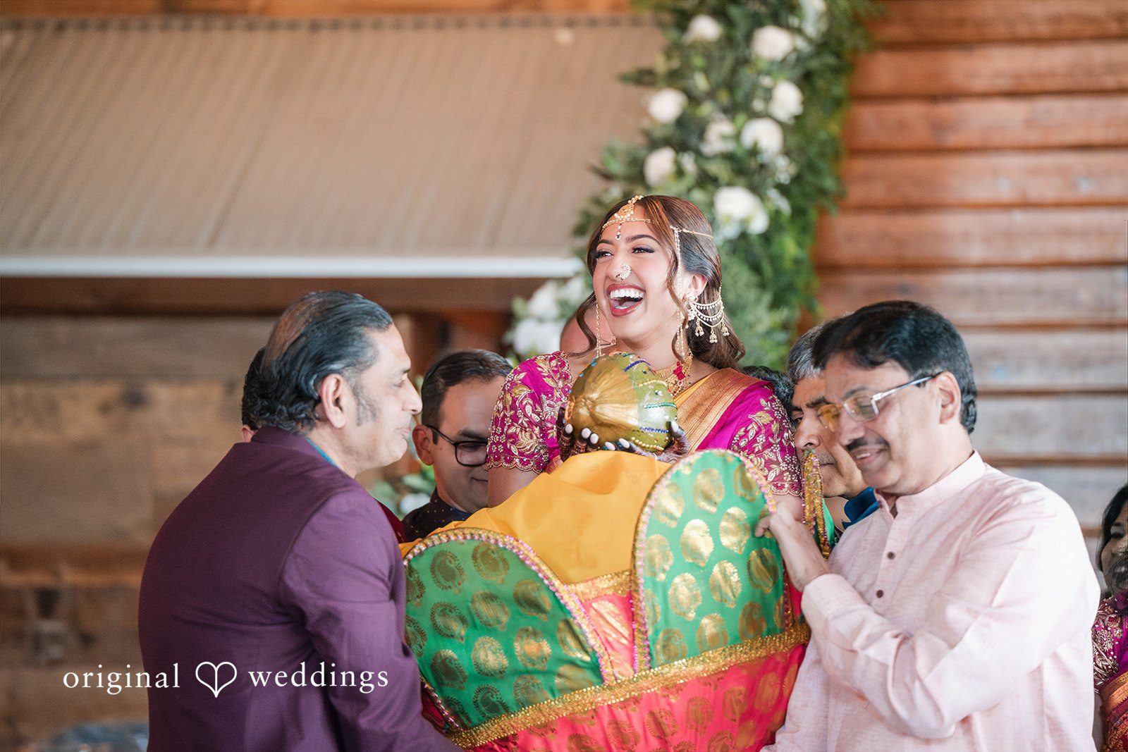 Bride in a green and gold outfit being carried by family members during a traditional ceremony.
