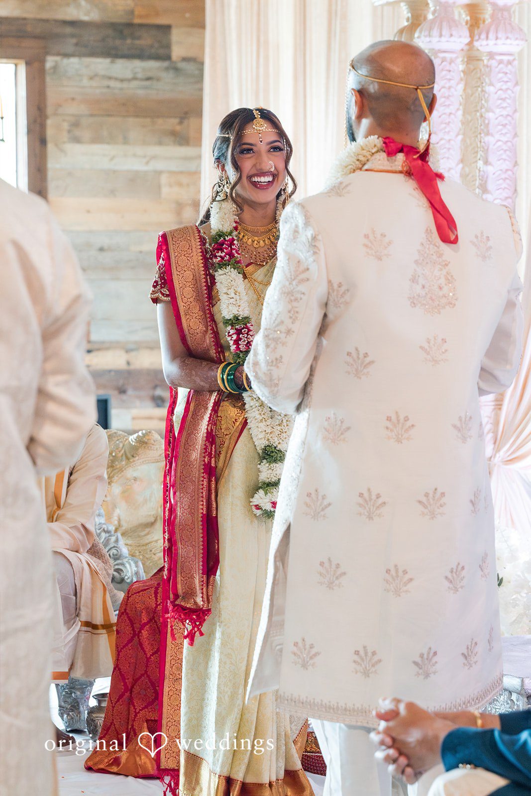 Groom facing the bride while holding her hands during a traditional wedding ritual.